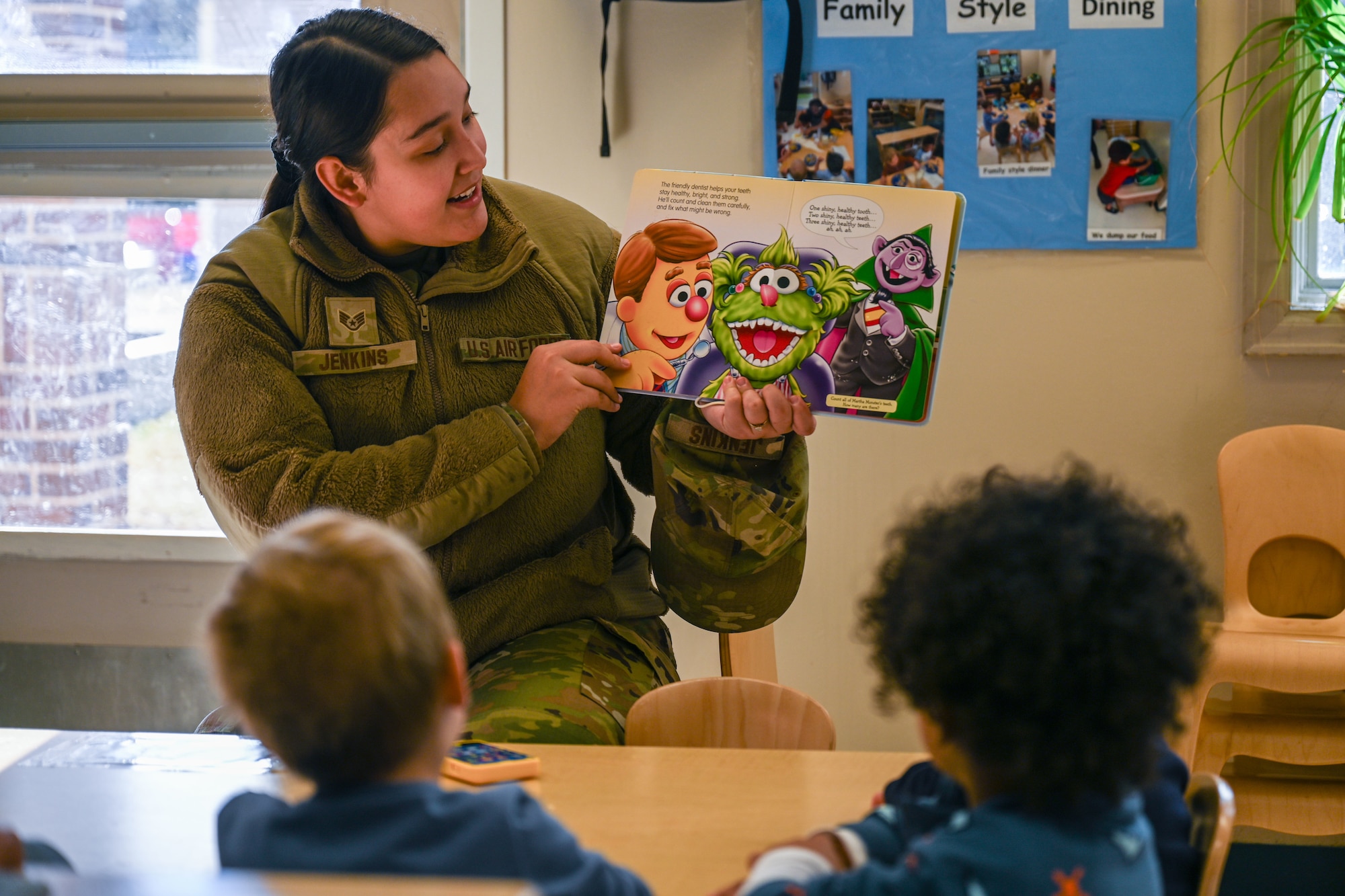 A servicemember reads a book to kids.
