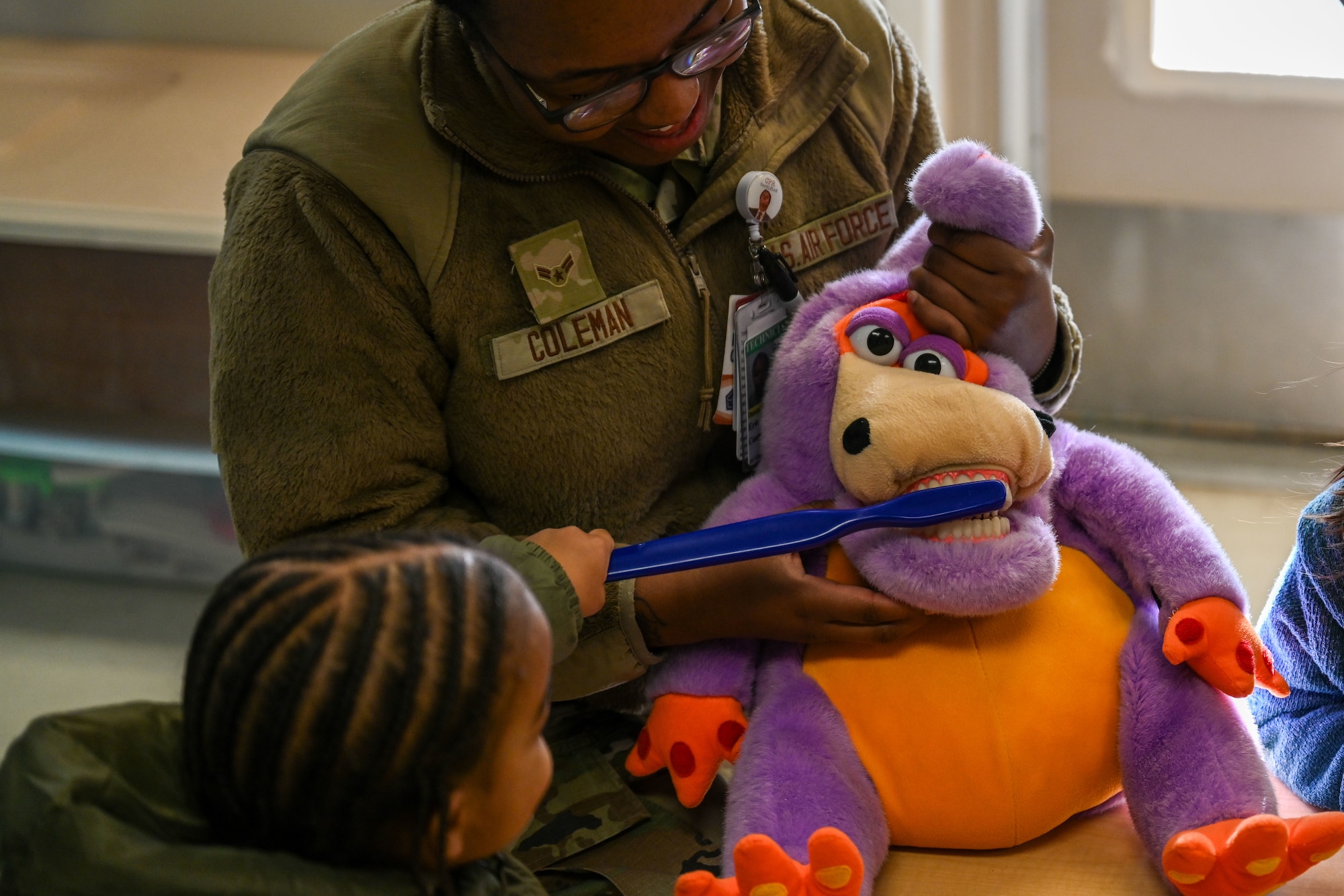 A child brushes teeth on a stuffed animal.