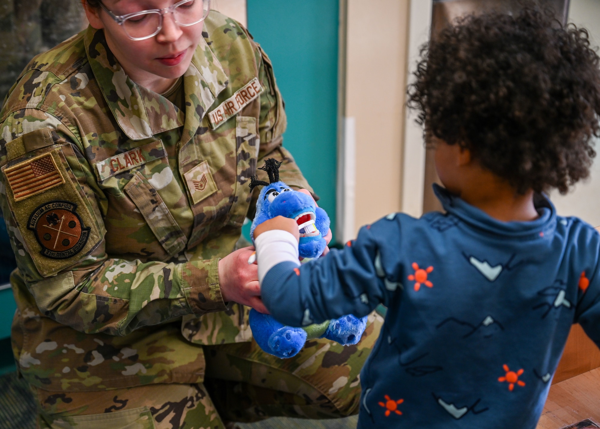 A child brushes teeth on a stuffed animal.