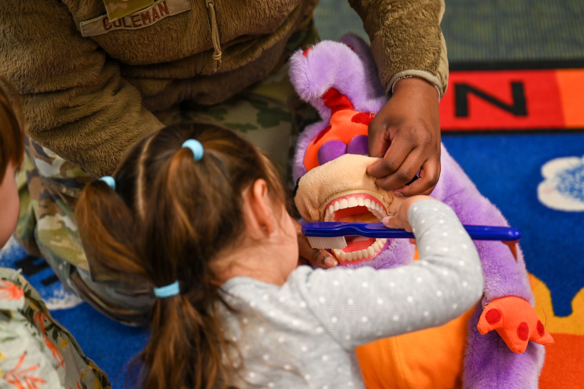 A child brushes teeth on a stuffed animal.