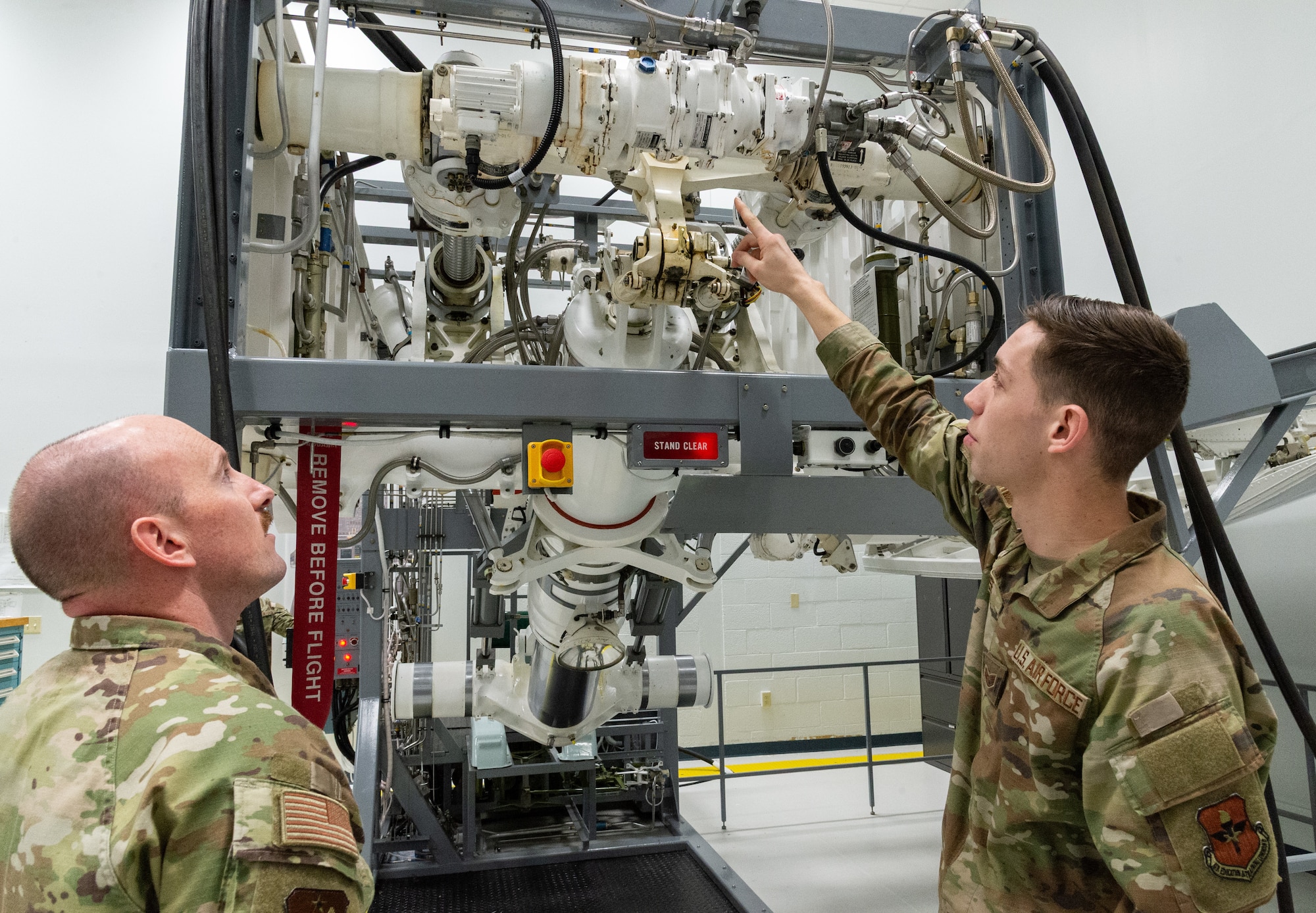 U.S. Air Force Master Sgt. Justin Goode, left, Air Force Career Development Academy learning engineer, watches Staff Sgt. Weston Rose, right, 373rd Training Squadron, Detachment 3 C-5M hydraulic instructor, describe components on the C-5 nose landing gear maintenance training device located at the 373rd TRS, Det 3 on Dover Air Force Base, Delaware, Feb. 12, 2026. Goode is in the process of developing Computer-Based Training micro-lessons for the 2A6X5 career field. (U.S. Air Force photo by Roland Balik)