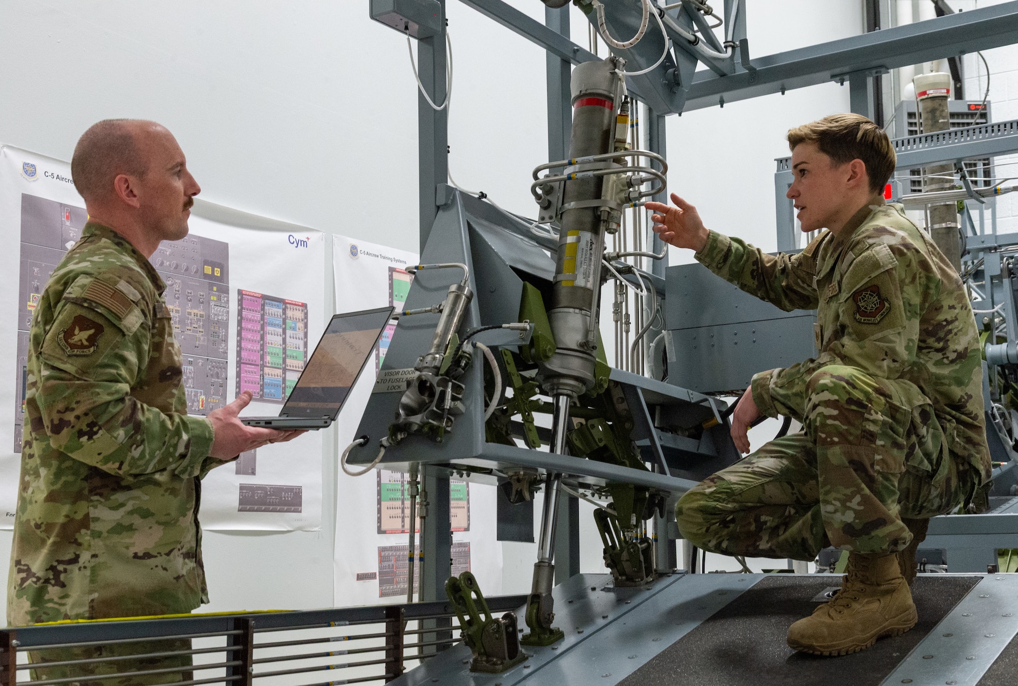 U.S. Air Force Master Sgt. Justin Goode, left, Air Force Career Development Academy learning engineer, listens to Tech. Sgt. Ashleigh Norris, right, 436th Maintenance Group Maintenance Qualification Training Program hydraulics instructor, describe components of the C-5 forward ramp maintenance training device located at the 373rd Training Squadron, Detachment 3 on Dover Air Force Base, Delaware, Feb. 12, 2026. Norris pointed out key hydraulic components of the forward ramp to ensure all imagery is captured for the development of aircraft hydraulic system Computer-Based Training micro-lessons. (U.S. Air Force photo by Roland Balik)
