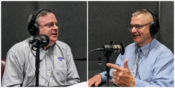 Two men record a podcast in a studio, speaking into microphones with headphones on and audio equipment around them.