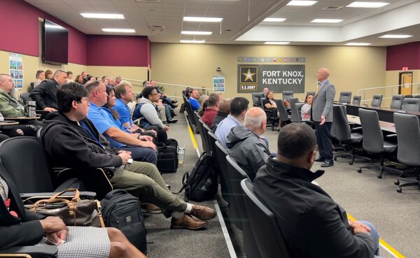 Adult students sit at tables in an Army Management Staff College classroom listening to an instructor give a lecture.