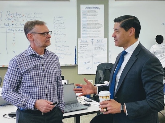 Two Army Management Staff College instructors stand at the front of a classroom talking during a professional development session.