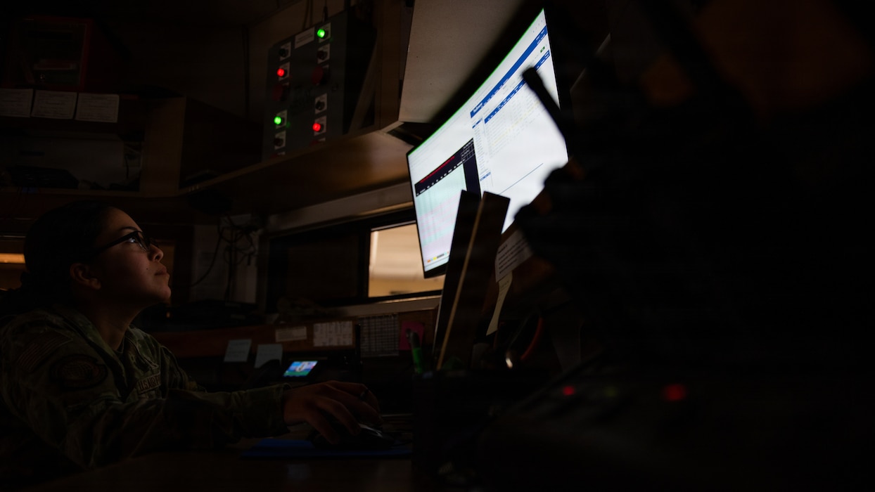 Airman viewing computer screen in the dark.