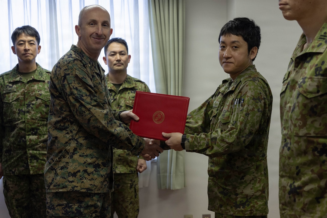 U.S. Marine Corps Maj. Matthew Forshee, left, the executive officer of Headquarters and Headquarters Squadron (HHS), Marine Corps Air Station Iwakuni and a native of Texas, gives a Japan Ground Self-Defense Force member with the 13th Brigade, Middle Army, a certificate of appreciation at Camp Kaitaichi, Hiroshima, Japan, Feb. 20, 2026. Members of the JGSDF were presented with a certificate of appreciation recognizing their support during exercise Nankai Rescue 2026. (U.S. Marine Corps photo by Lance Cpl. Ella Cadby)