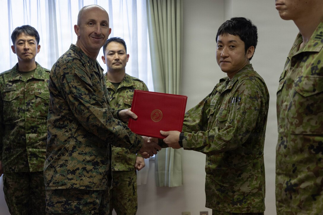 U.S. Marine Corps Maj. Matthew Forshee, left, the executive officer of Headquarters and Headquarters Squadron (HHS), Marine Corps Air Station Iwakuni and a native of Texas, gives a Japan Ground Self-Defense Force member with the 13th Brigade, Middle Army, a certificate of appreciation at Camp Kaitaichi, Hiroshima, Japan, Feb. 20, 2026. Members of the JGSDF were presented with a certificate of appreciation recognizing their support during exercise Nankai Rescue 2026. (U.S. Marine Corps photo by Lance Cpl. Ella Cadby)