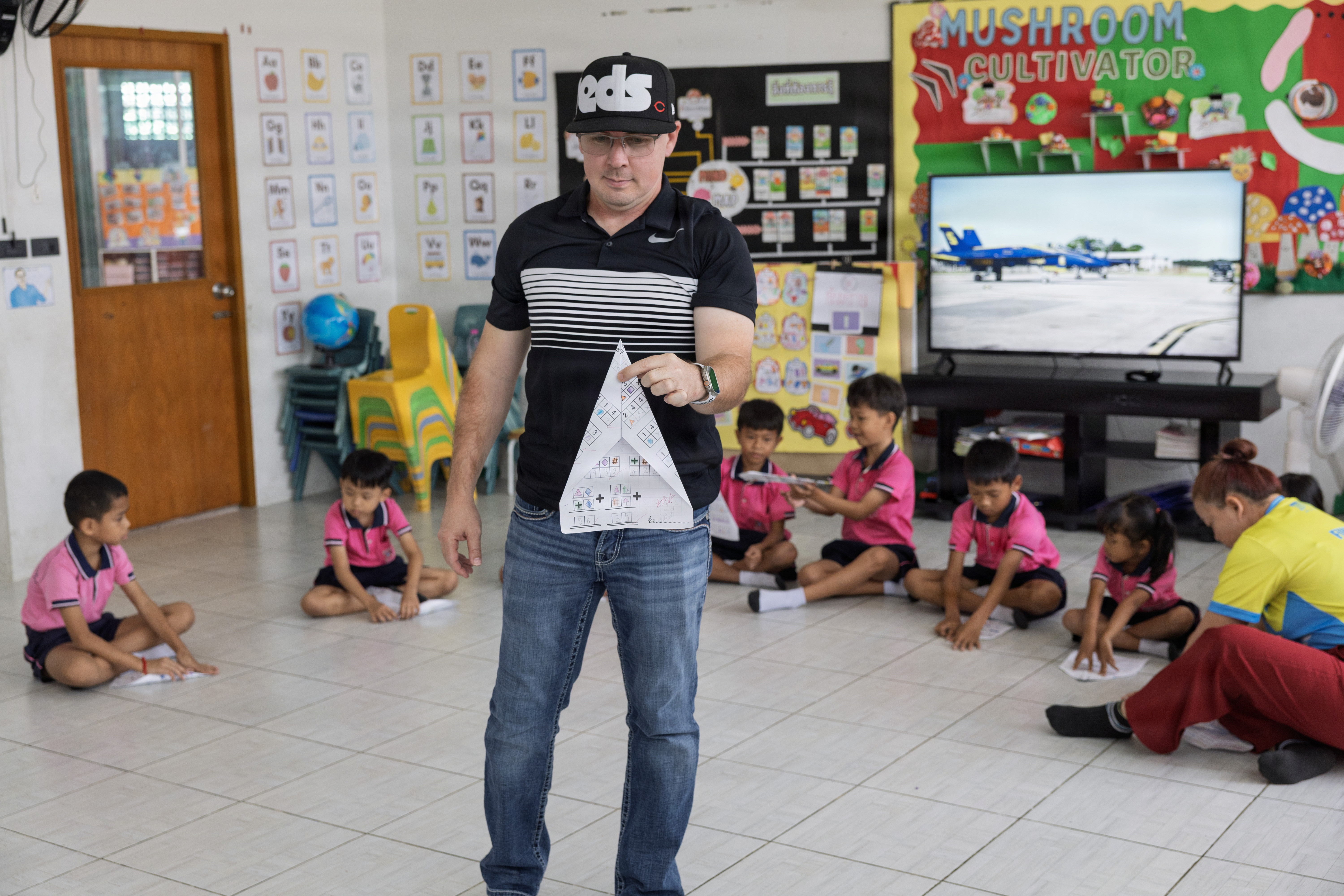 U.S. Navy Reserve Lt. Cmdr. Joe Morris, Military Sealift Command Navy Reserve Expeditionary Port Unit Little Rock, Ark., MSC Far East, demonstrates building a paper airplane to kids of the Learning Center, Human Help Network, during a community relations event at Pattaya, Thailand, Feb. 16, 2026.