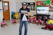 U.S. Navy Reserve Lt. Cmdr. Joe Morris, Military Sealift Command Navy Reserve Expeditionary Port Unit Little Rock, Ark., MSC Far East, demonstrates building a paper airplane to kids of the Learning Center, Human Help Network, during a community relations event at Pattaya, Thailand, Feb. 16, 2026.