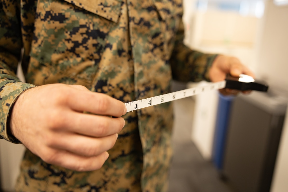 A U.S. Marine with Training and Education Command poses with a retractable measuring tape used for body composition assessment at Marine Corps Base Quantico, Virginia, Feb. 6, 2026. The Marine Corps is replacing the current semiannual height and weight screening with a waist-to-height ratio (WHtR) methodology as the initial step in its body composition evaluation process, in accordance with recent guidance from the Secretary of War. (U.S. Marine Corps photo by SSgt. Claudia Nix)