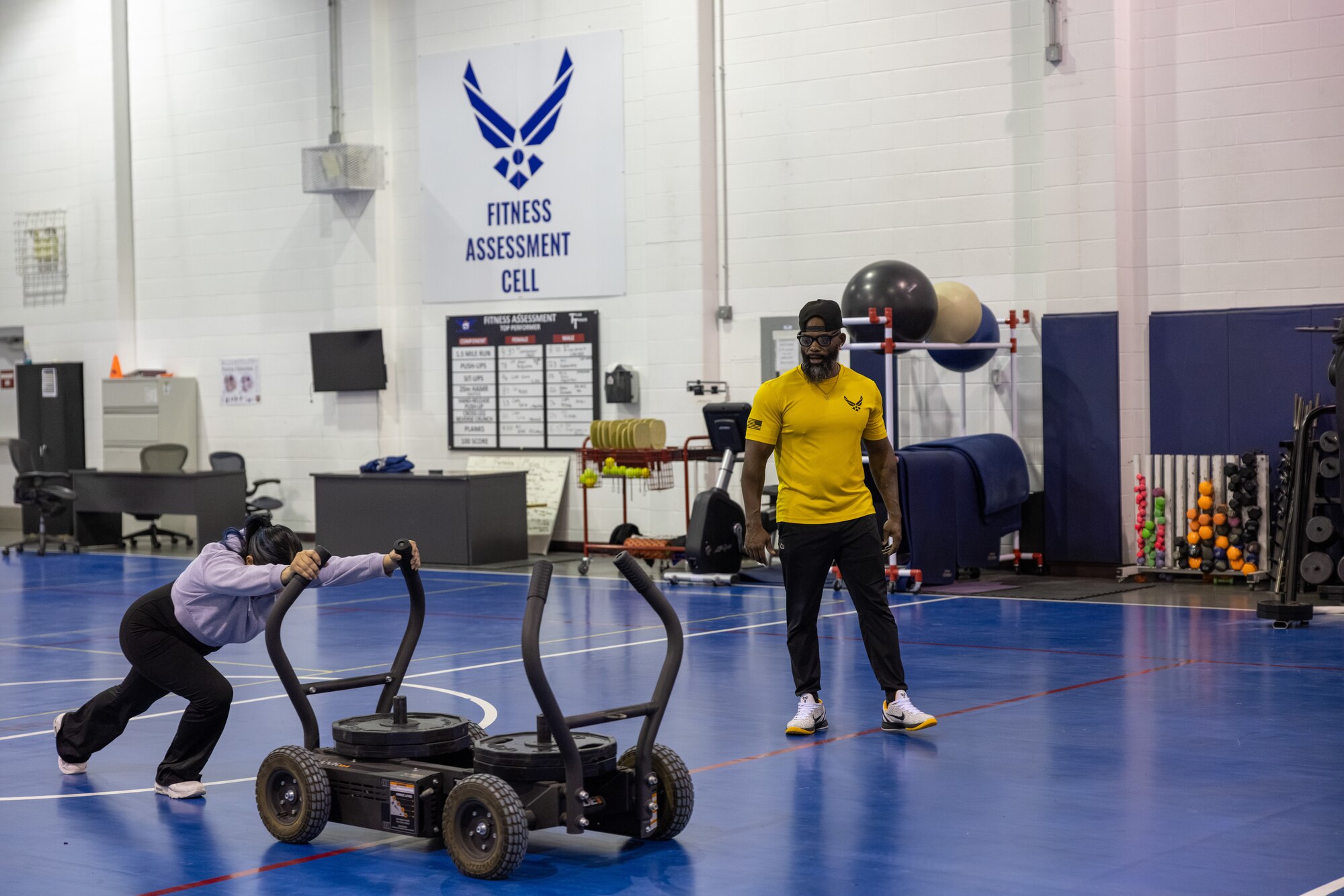 Woman works out as man trains her.