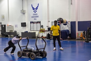 Woman works out as man trains her.