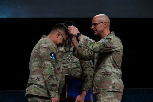 U.S. Space Force Chief of Space Operations Gen. Chance Saltzman, left, and Chief Master Sgt. of the Space Force John Bentivegna, right, recognize Sgt. Michael Campos at the Air Force Association’s Warfare Symposium in Aurora, Colo., Feb. 23, 2026. Campos was awarded the Connection Award, one of four Guardian Values included in the Space Force’s annual Polaris Awards. (U.S. Air Force photo by Senior Airman Malia Heemsoth)