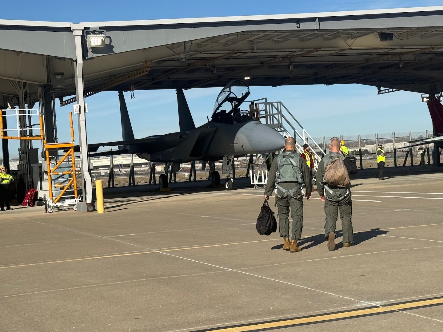 Two men in flight suits walk toward a plane