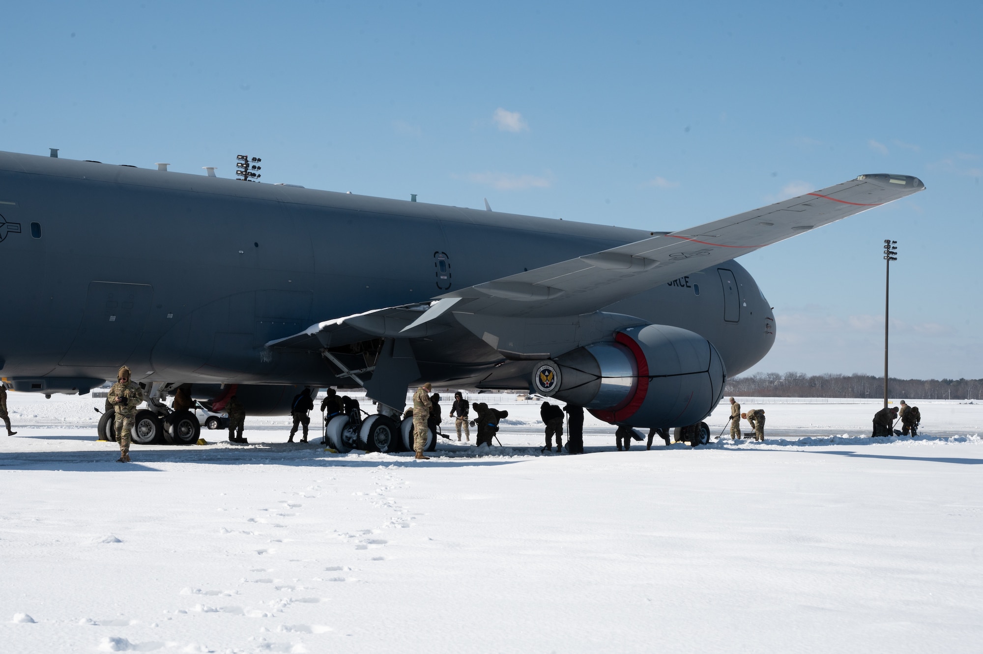 Airmen from the 305th Air Mobility Wing shovel snow and clear a path for the wheels of KC-46A Pegasus on Joint Base McGuire-Dix-Lakehurst, N.J., Feb. 24, 2026. Even in times of inclement weather, mission essential personnel maintained operational readiness of the base. (U.S. Air Force photo by Airman 1st Class Matthew Almazan)