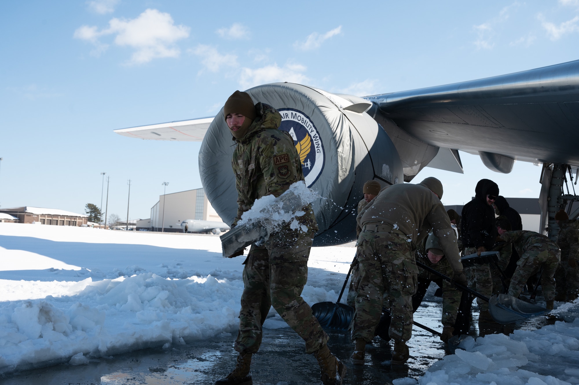 U.S. Air Force Airman Wade Riggle, 605th Aircraft Maintenance Squadron crew chief, shovels snow from under a KC-46A Pegasus on Joint Base McGuire-Dix-Lakehurst, N.J., Feb. 24, 2026. Even as Winter Storm Hernando impacted the area, teams maintained operational readiness across flight lines, roadways and support facilities. (U.S. Air Force photo by Airman 1st Class Matthew Almazan)