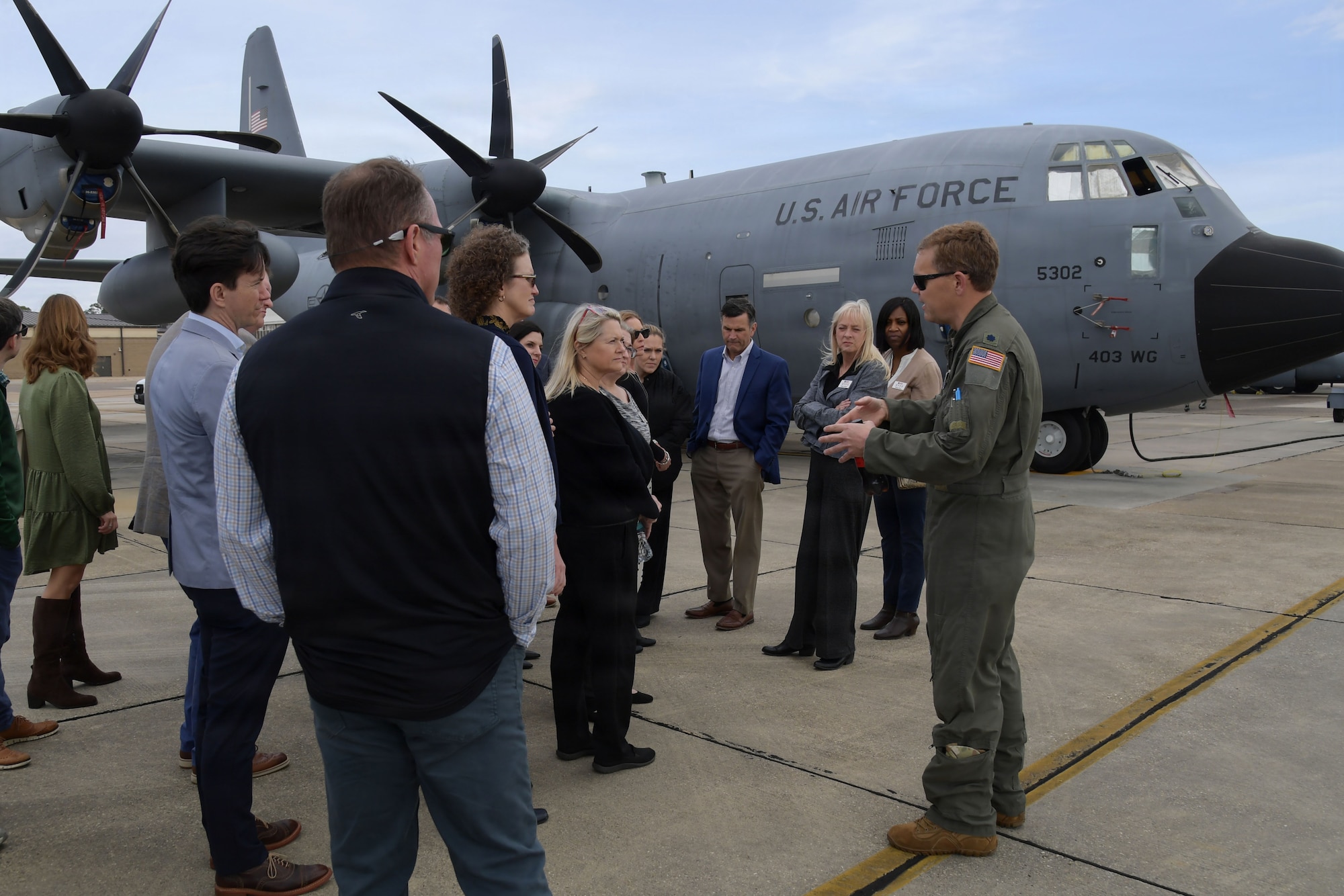 An Air Force pilot speaks to a group of people in front of an aircraft.