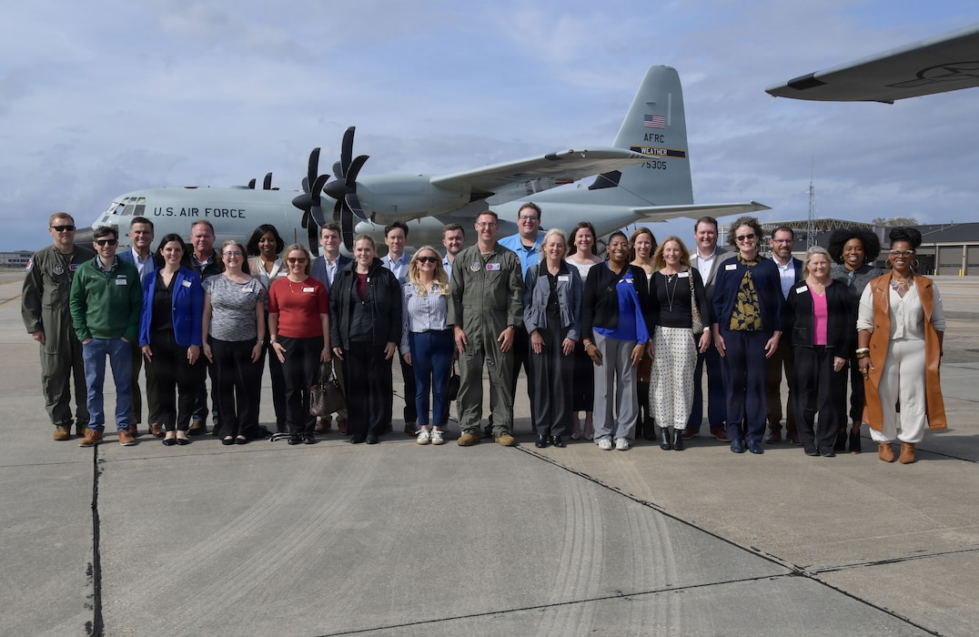 A group of people pose for a photo in front of a WC-130J Super Hercules aircraft.