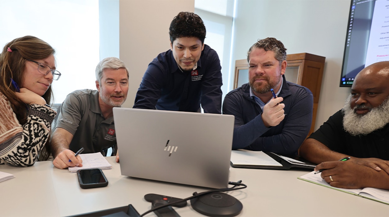 Picture of 5 people looking at a laptop.