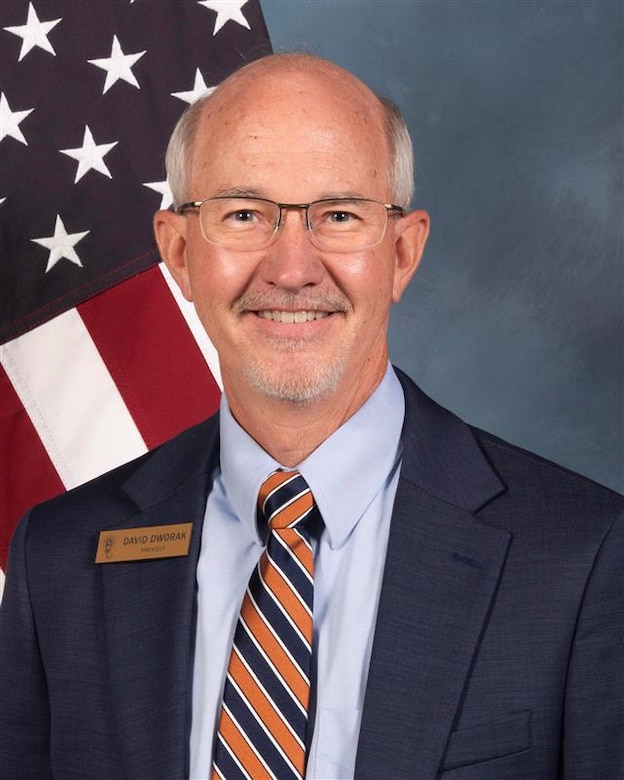 Photo of a man in front of a flag and blue background.