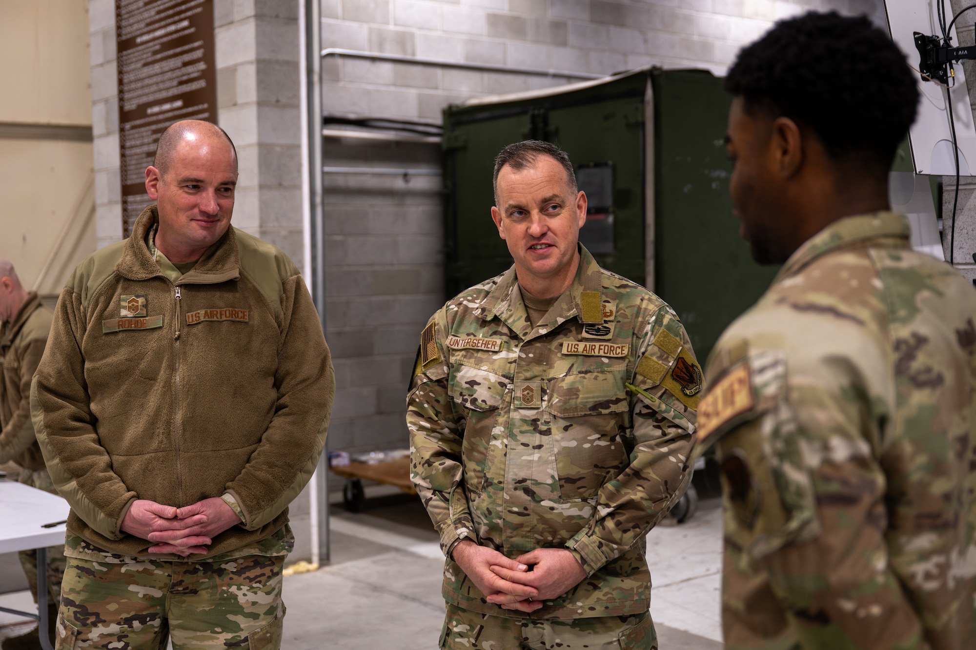 The two Command Chiefs stand together in conversation with an Airman