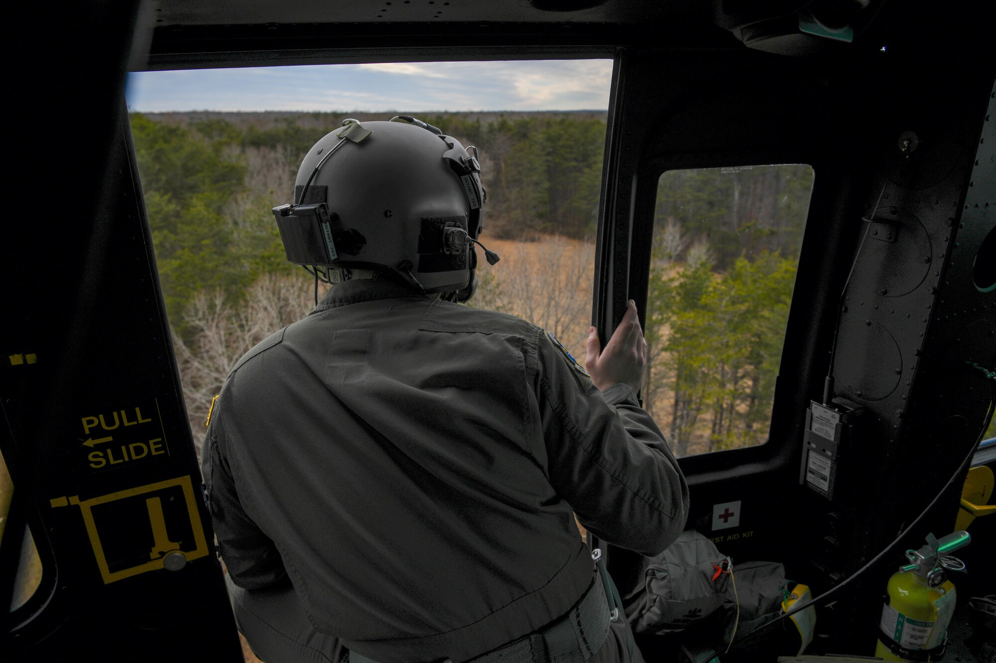 Service members looks out from helicopter