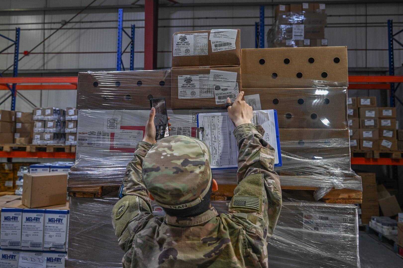 person in uniform reaches for boxes on pallet