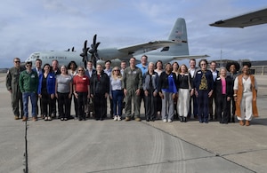 A group of people pose for a photo in front of a WC-130J Super Hercules aircraft.