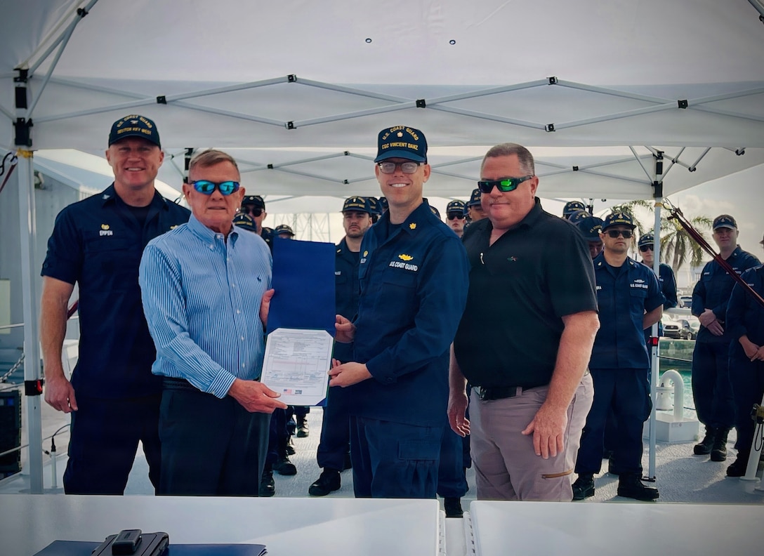 Lt. Cmdr. Brendan Kelley (right center), commanding officer of USCGC Vincent Danz (WPC 1162), stands with Allen Harker (left), contracting officer for the Fast Response Cutter Project, and assembled crew and guests in Key West, Florida, on Feb. 26, 2026, after signing for the acceptance of the U.S. Coast Guard's newest cutter. The cutter is named for Vincent Danz, a New York City police officer and U.S. Coast Guard reservist who made the ultimate sacrifice on Sept. 11, 2001, while responding to the attacks on the World Trade Center. (U.S. Coast Guard photo)