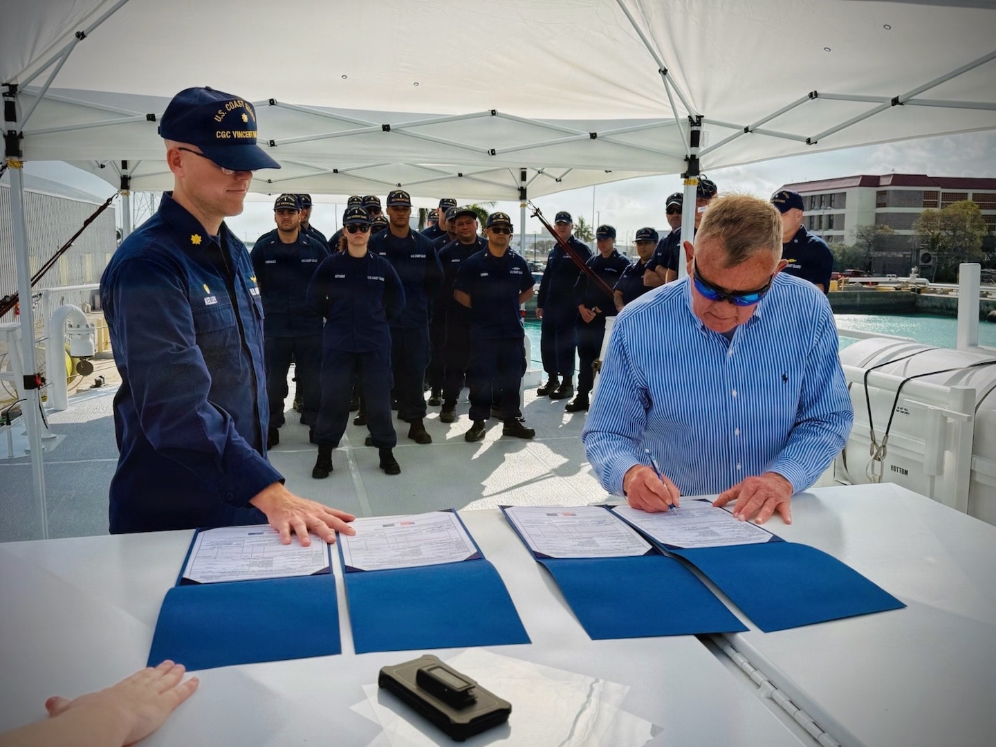 Lt. Cmdr. Brendan Kelley (left), commanding officer of USCGC Vincent Danz (WPC 1162), looks on as Allen Harker (right), contracting officer for the Fast Response Cutter Project, signs the acceptance of the cutter during a ceremony in Key West, Florida, on Feb. 26, 2026. The cutter is named for Vincent Danz, a New York City police officer and U.S. Coast Guard reservist who made the ultimate sacrifice on Sept. 11, 2001, while responding to the attacks on the World Trade Center. (U.S. Coast Guard photo)