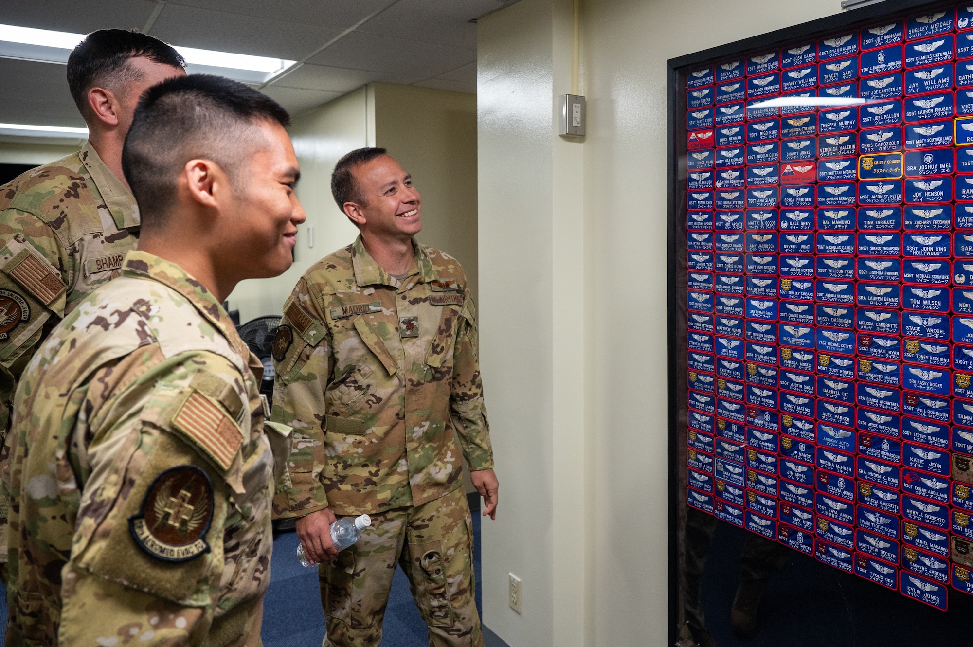 U.S. Air Force Capt. David Madrid, right, 18th Aeromedical Evacuation Squadron training flight commander, and U.S. Air Force Senior Airman Angelo Libunao, 18th AES AE technician, views a wall of past flyer’s name tags at Kadena Air Base, Feb. 19, 2026. Libunao recently joined the 18th AES, following in the footsteps of his father and uncle who also served in the unit. (U.S. Air Force photo by Airman 1st Class Francisco Huerta)
