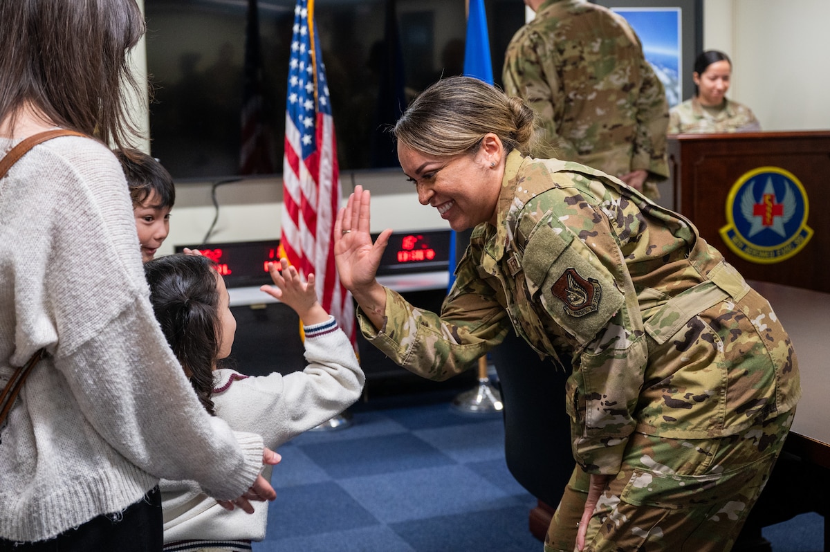 U.S. Air Force Col. Jeanae Jackson, 18th Aeromedical Evacuation Squadron commander high-fives a sibling of Senior Airman Angelo Libunao following a recognition ceremony at Kadena Air Base, Feb. 19, 2026. Libunao became the third member of his family to serve in the 18th Aeromedical Evacuation Squadron, continuing a multigenerational legacy of service at Kadena. (U.S. Air Force photo by Airman 1st Class Francisco Huerta)