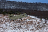 A man wearing a camouflage military uniform prepares for a parachute jump outside in a snow covered field.
