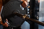 A patron loads a weight plate onto a barbell at the fitness center at Travis Air Force Base, California, Feb. 24, 2026. Airmen and patrons use the fitness center for individual physical training and fitness activities. (U.S. Air Force photo by Kenneth Abbate)