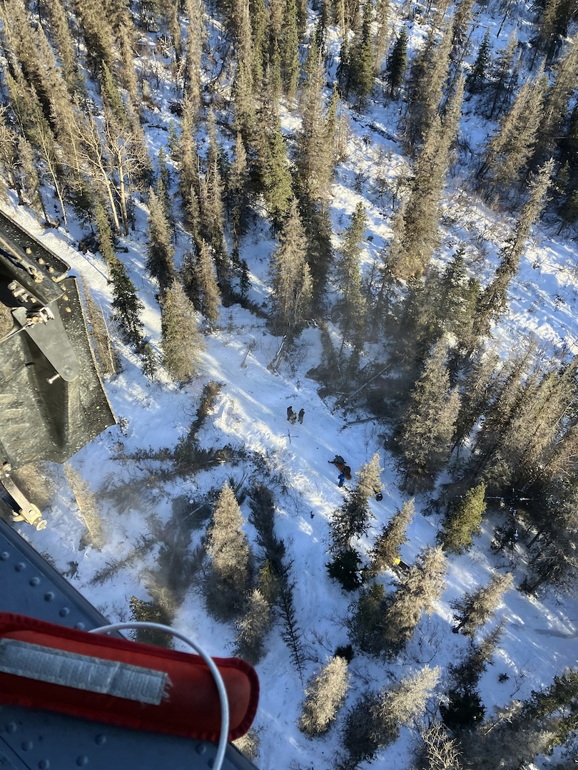 Alaska Air National Guard pararescuemen assigned to the 212th Rescue Squadron prepare to hoist an injured snowmachiner from a heavily wooded, mountainous area near Cooper Landing, Alaska, Feb. 21, 2026.