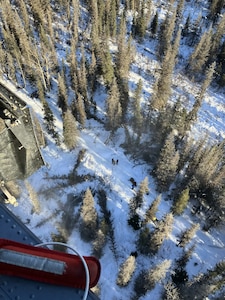 Alaska Air National Guard pararescuemen assigned to the 212th Rescue Squadron prepare to hoist an injured snowmachiner from a heavily wooded, mountainous area near Cooper Landing, Alaska, Feb. 21, 2026.