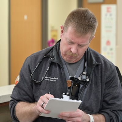 Navy Lt. Bradley Vander Zanden, a family medicine resident at Carl R. Darnall Army Medical Center, writes notes while speaking to a nurse. Residents at the hospital train across multiple specialties while caring for service members, retirees, and their families.