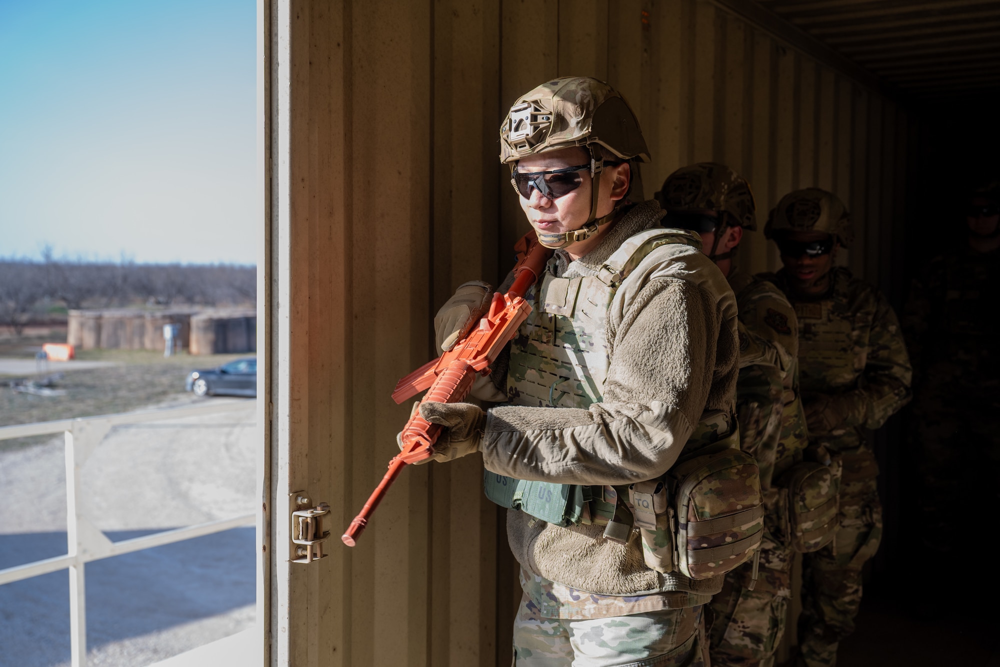 U.S. Air Force Senior Airman Jordan Chau, 21st Combat Air Base Squadron water and fuels maintenance specialist, looks out of a doorway while participating in a close quarters battle training scenario during exercise Bamboo Eagle 26-1 at Dyess Air Force Base, Texas, Feb. 20, 2026. Airmen practiced entry techniques, sector coverage and threat response in controlled scenarios during CQB training,  replicating real-world contested environments. (U.S. Air Force photo by Airman 1st Class Adrien Tran)