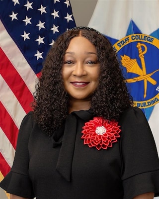 Civilian federal leader posed for a formal portrait with the Army Management Staff College emblem in the background.