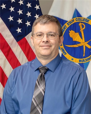 Civilian federal leader posed for a formal portrait with the Army Management Staff College emblem in the background.