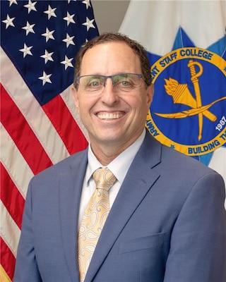 Civilian federal leader posed for a formal portrait with the Army Management Staff College emblem in the background.