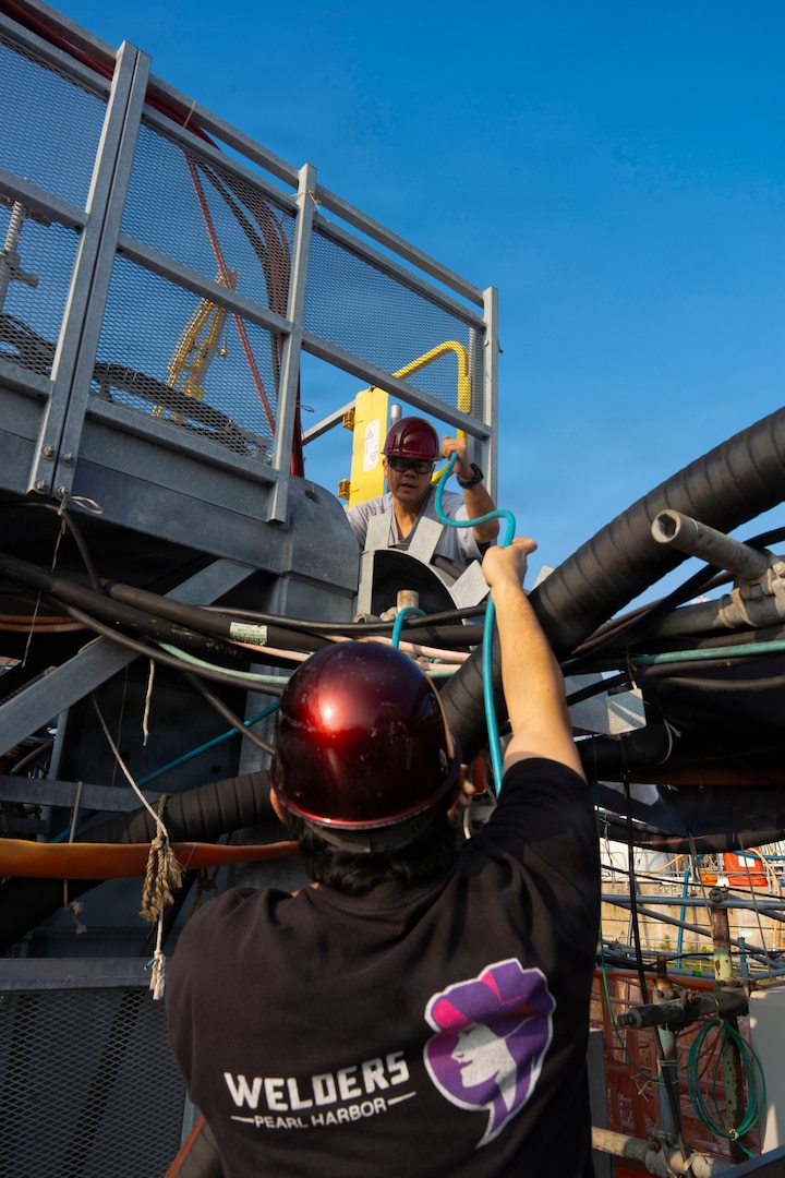 From top, Ryan Togami and Bronson Kimata, nuclear welders with Pearl Harbor Naval Shipyard and Intermediate Maintenance Facility, run a gas line to their job site in dry dock 1 at the shipyard Jan. 28, 2026.