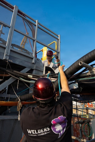 From top, Ryan Togami and Bronson Kimata, nuclear welders with Pearl Harbor Naval Shipyard and Intermediate Maintenance Facility, run a gas line to their job site in dry dock 1 at the shipyard Jan. 28, 2026.
