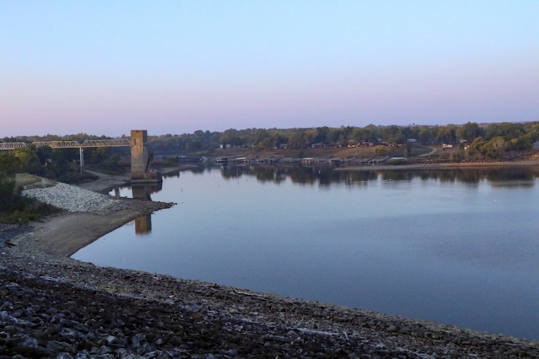 A body of water with a concrete tower to the left and trees in the background.