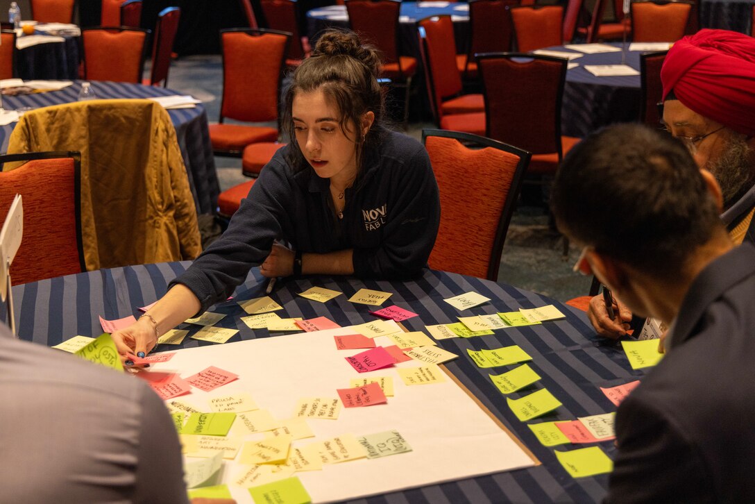 Rayna Roades, a student panelist from Northern Virginia Community College, participates in a Collaboration Workshop during the SIDE 2026: A Deep Dive into 3D Scanning industry partnership forum. Roades and other attendees, including industry leaders and personnel from Naval Surface Warfare Center, Carderock Division, used sticky notes to brainstorm and discuss potential partnership opportunities.