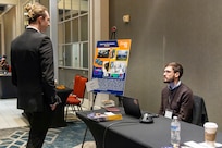 NORTH BETHESDA, Maryland (Feb. 25, 2026) – A Naval Surface Warfare Center, Carderock Division employee explains his department's work to an attendee during Carderock's Industry Day. The event was co-hosted by Carderock and the Pike District Partnership with support from the Montgomery County Economic Development Corporation. Carderock, the Navy's innovation and ship design powerhouse, headquartered in West Bethesda, Maryland, is a world-class research and development facility specializing in critical ship and ship systems design. (U.S. Navy photo by Aaron Thomas)