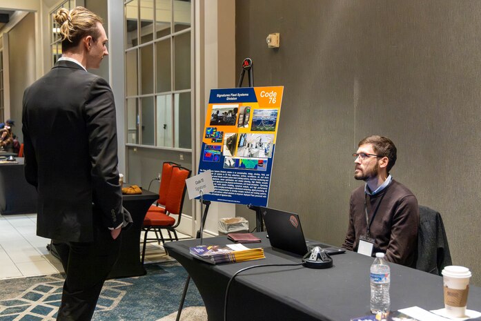 NORTH BETHESDA, Maryland (Feb. 25, 2026) – A Naval Surface Warfare Center, Carderock Division employee explains his department's work to an attendee during Carderock's Industry Day. The event was co-hosted by Carderock and the Pike District Partnership with support from the Montgomery County Economic Development Corporation. Carderock, the Navy's innovation and ship design powerhouse, headquartered in West Bethesda, Maryland, is a world-class research and development facility specializing in critical ship and ship systems design. (U.S. Navy photo by Aaron Thomas)