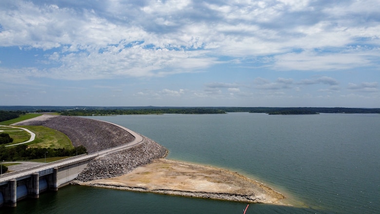 A body of water with sand in the foreground and a road on the left hand side.