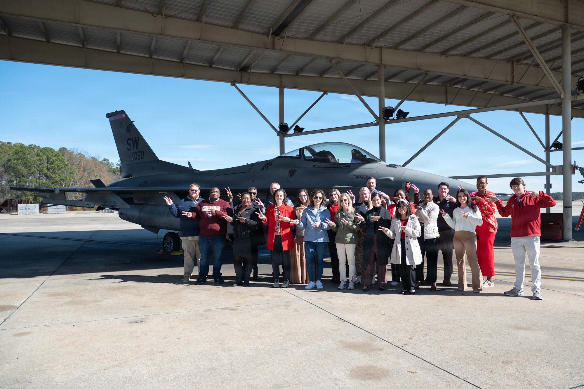 Civilians pose for a group photo in front of a fighter jet